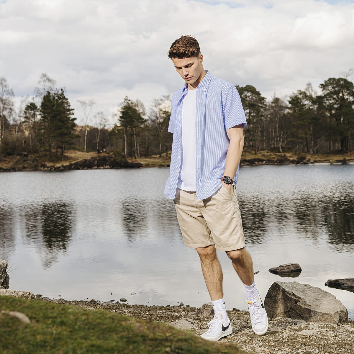 Man in Ralph Lauren shirt stands at the edge of a lake