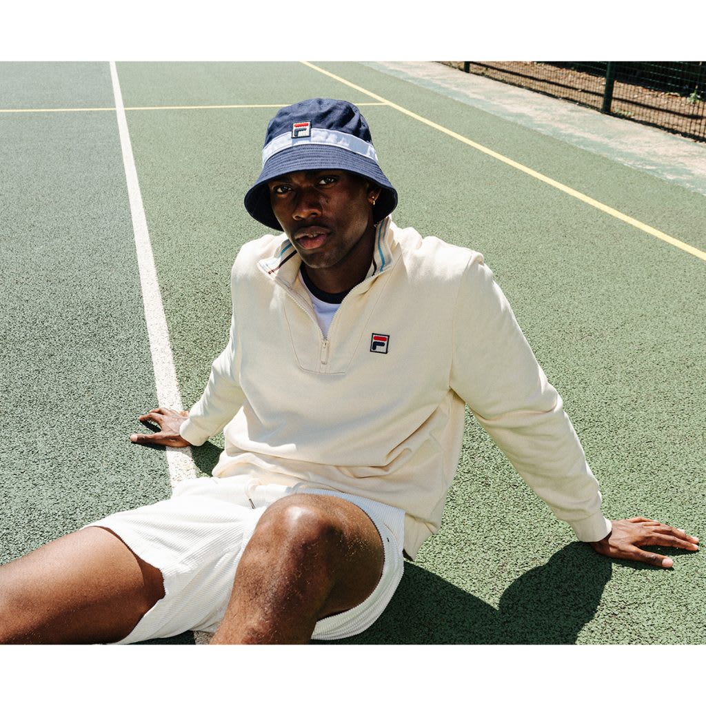 Man dressed in white sitting down on a tennis court