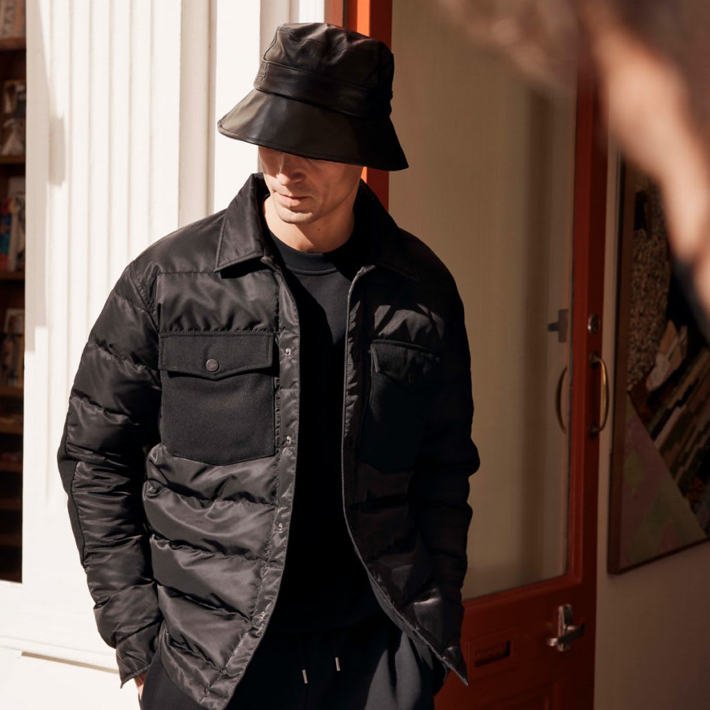 A man dressed in a black Ted Baker jacket and bucket hat