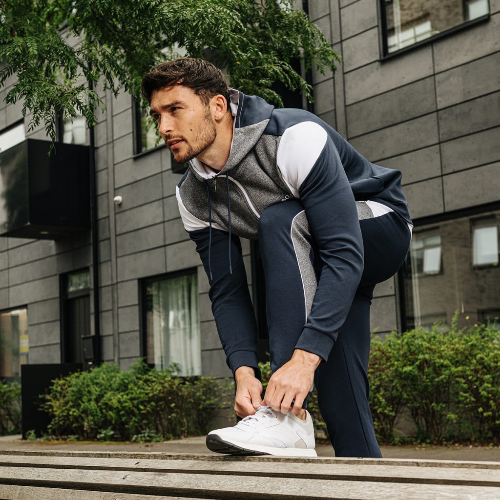 A man dressed in activewear tying his shoelaces