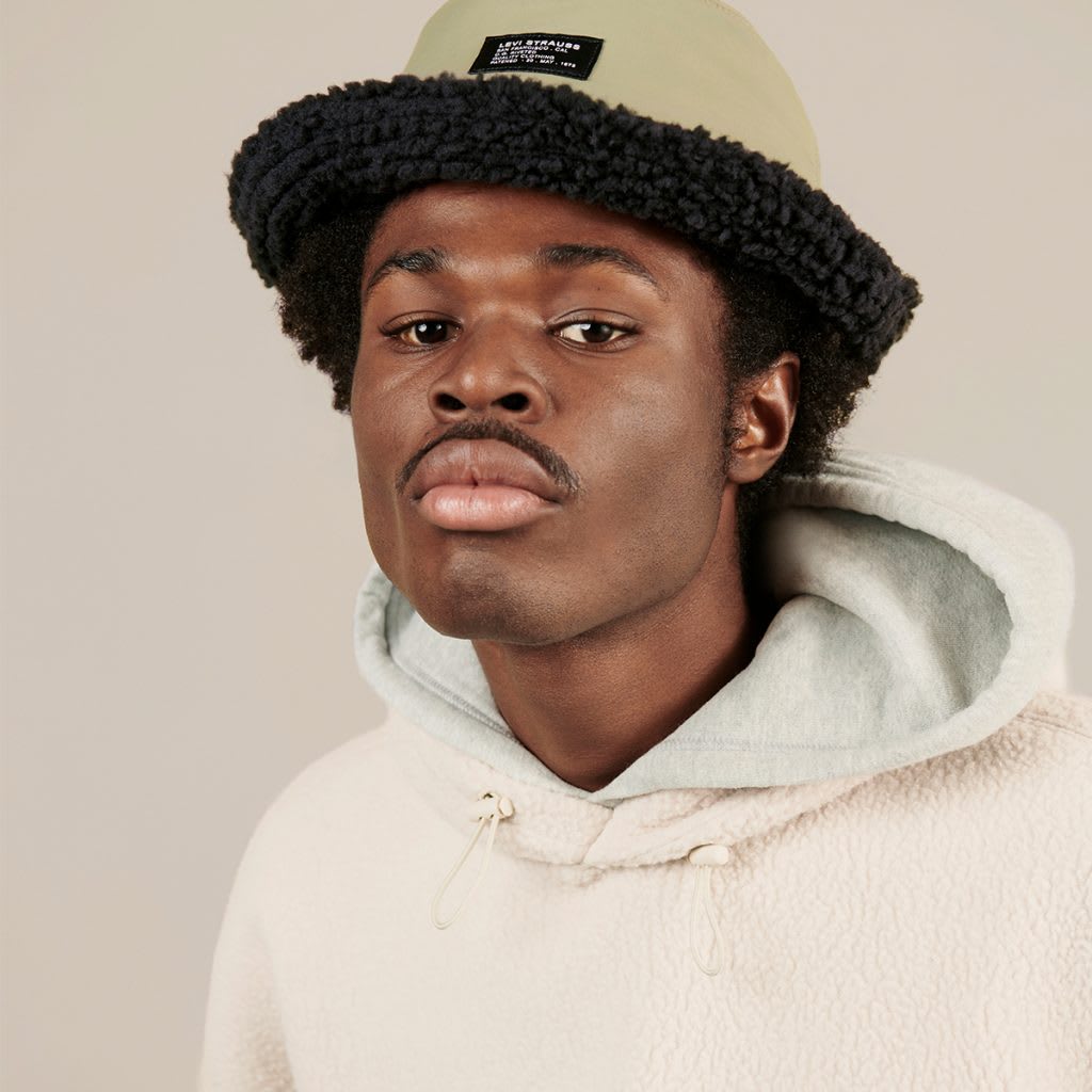 A man wearing a cream Levi's jumper and hat
