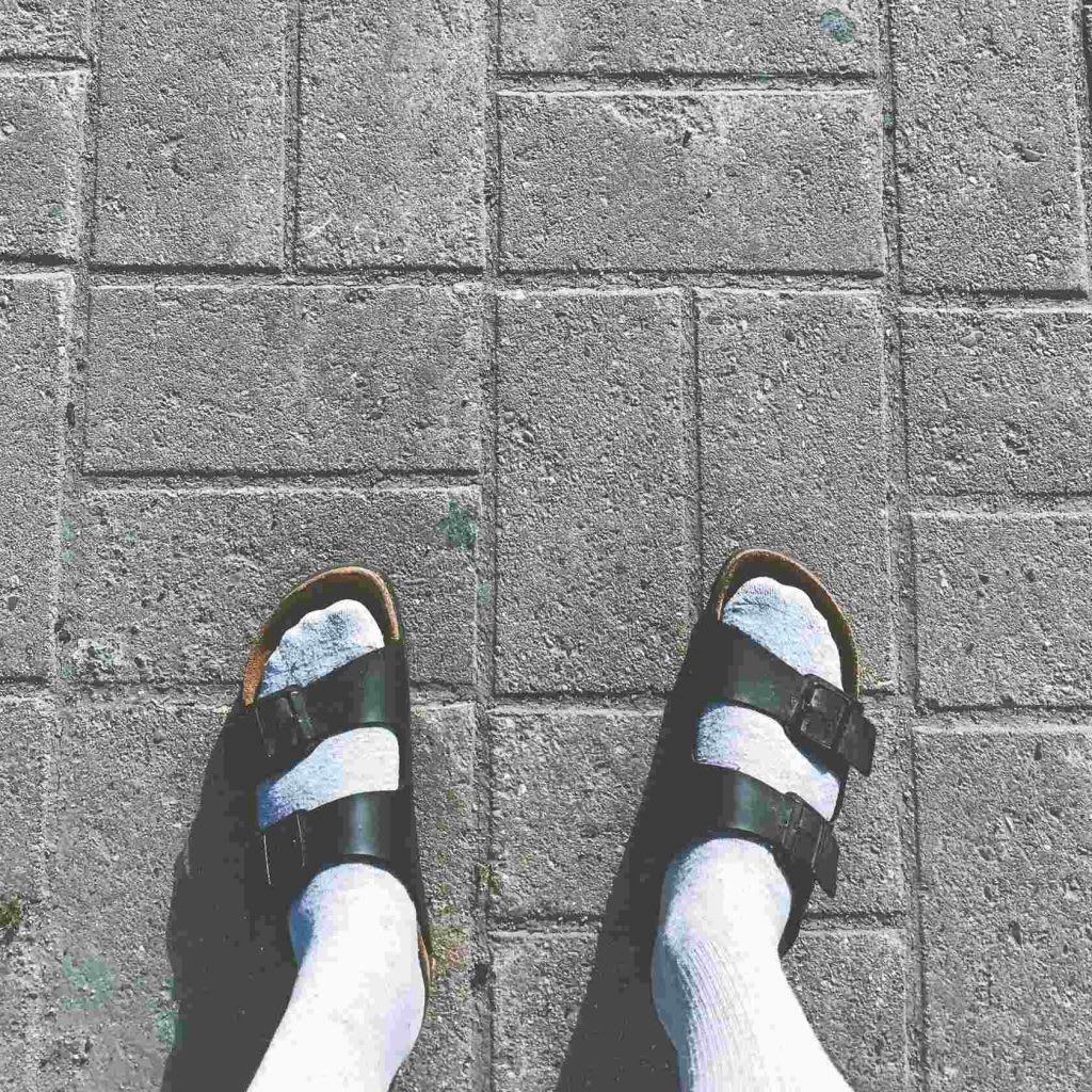 A top-down view of socked feet in sandals