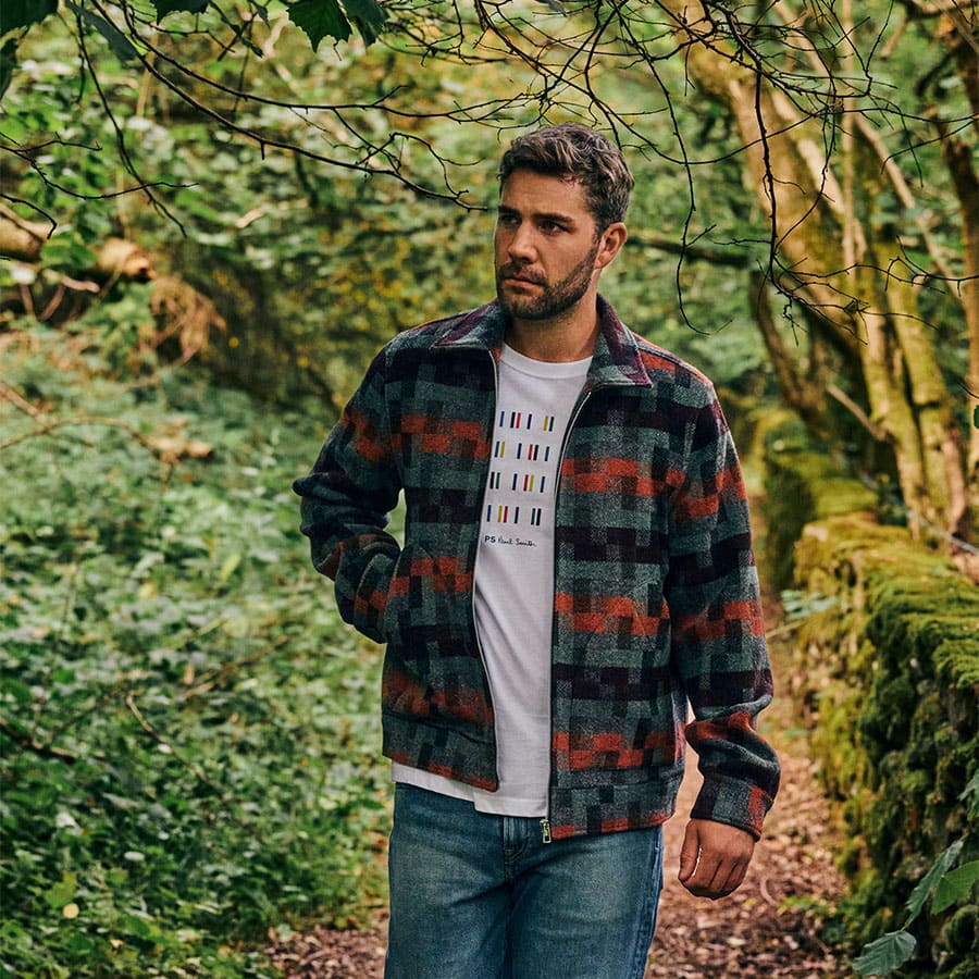 A man dressed in a layered outfit walking in the woods