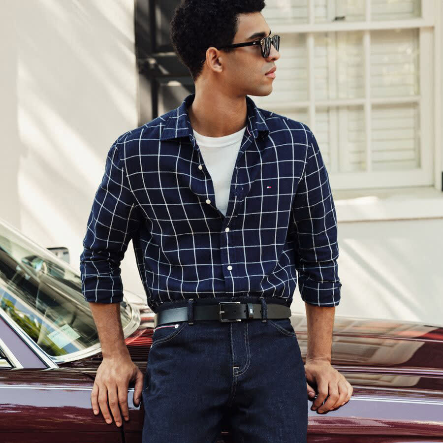 A man leaning against a car wearing a Tommy Hilfiger outfit.