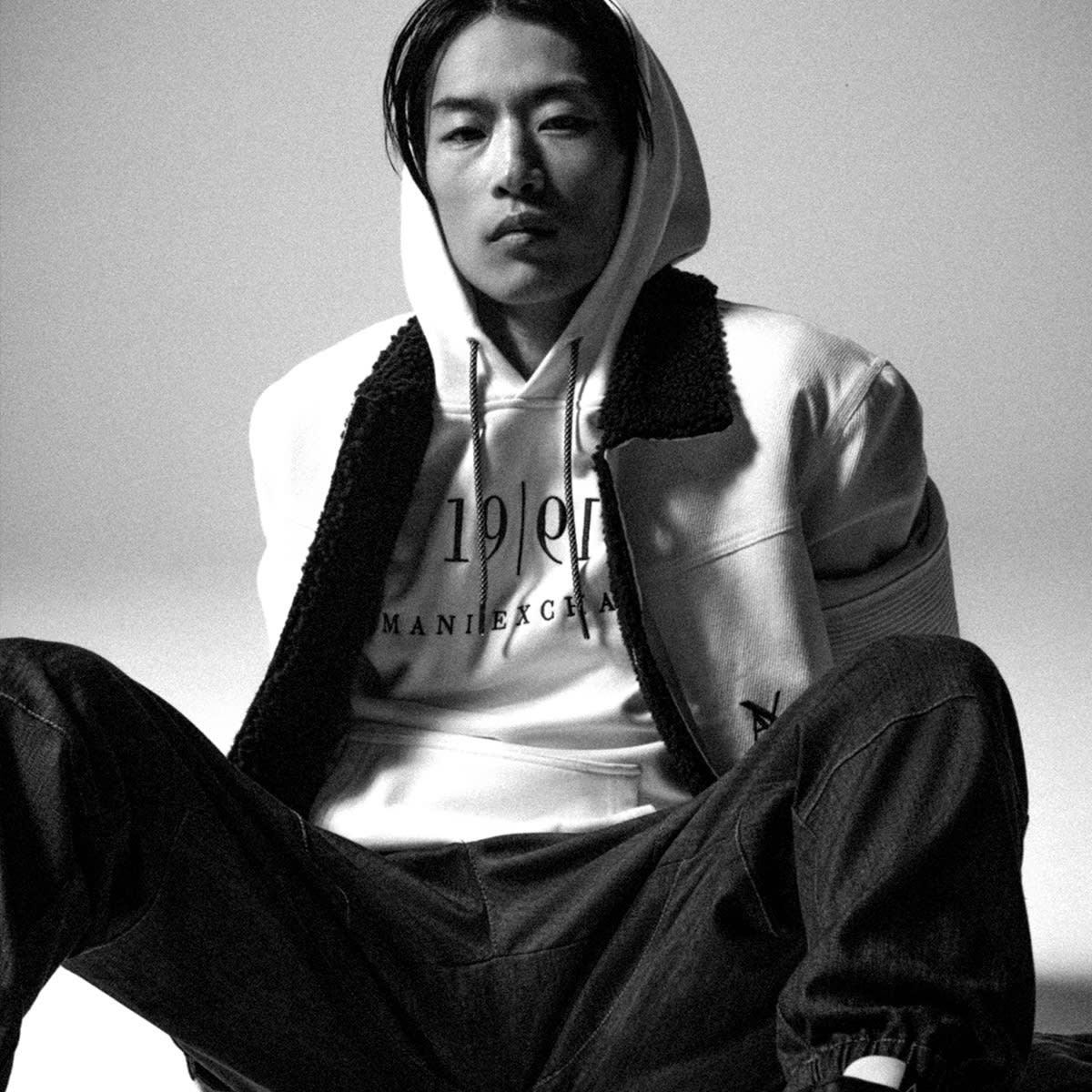A man sitting down dressed in an Armani Exchange hoodie and jeans
