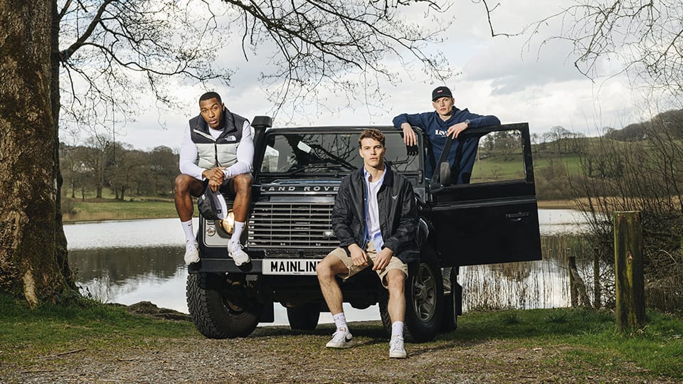 Three friends gathered around a Land Rover