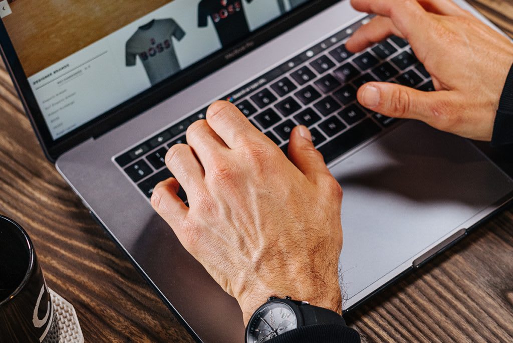 Hands typing on a laptop keyboard purchasing clothing on Singles Day