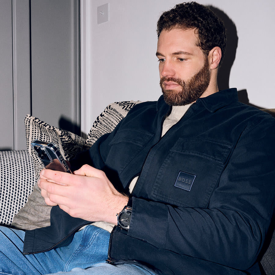 A man sitting down using hiss phone to order some new designer clothes