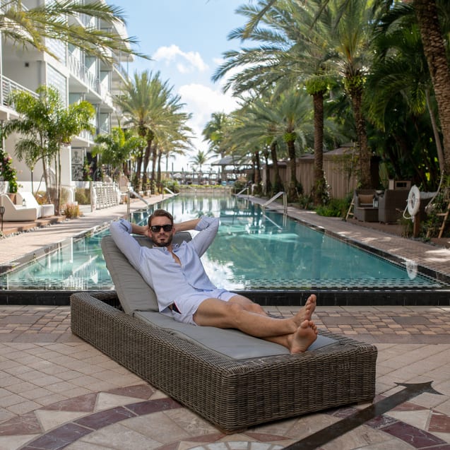 A man lying down wearing shorts by a pool
