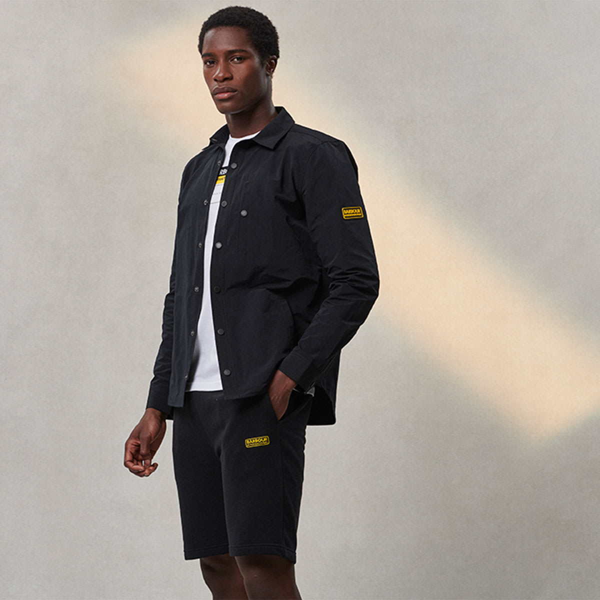 A man dressed in Barbour International clothing against a grey background.