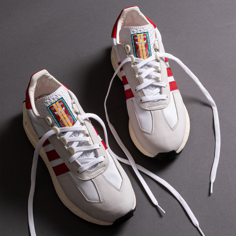 A pair of white trainers with red trim and fresh laces