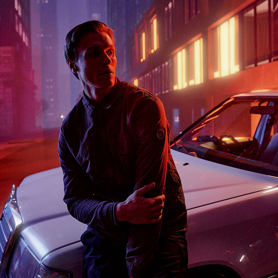 A man leaning on his car wearing designer clothes