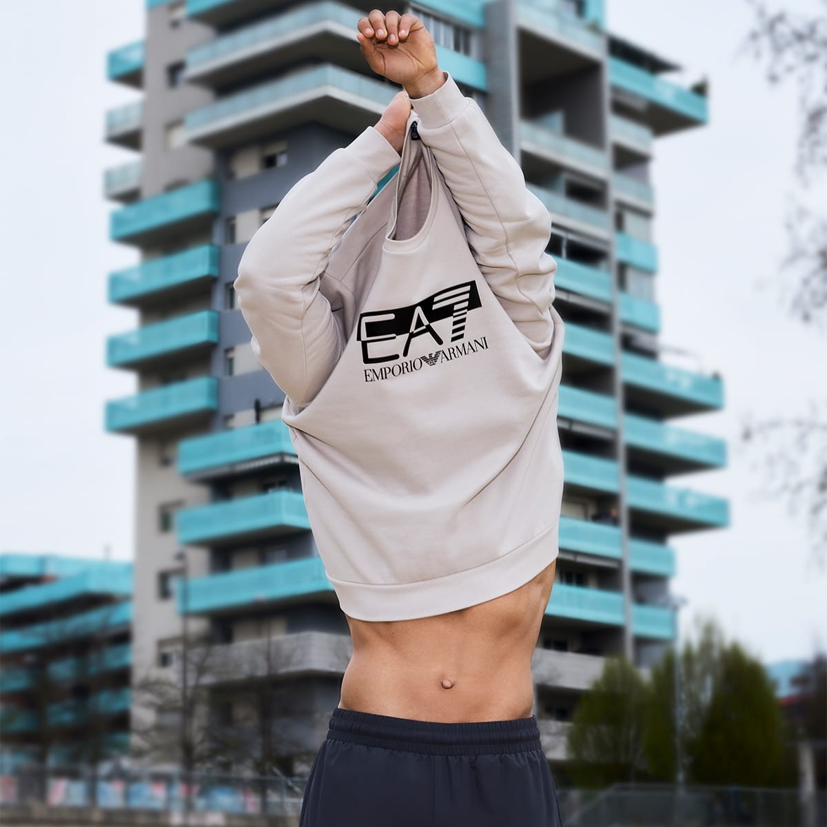 A man taking off an EA7 sweatshirt
