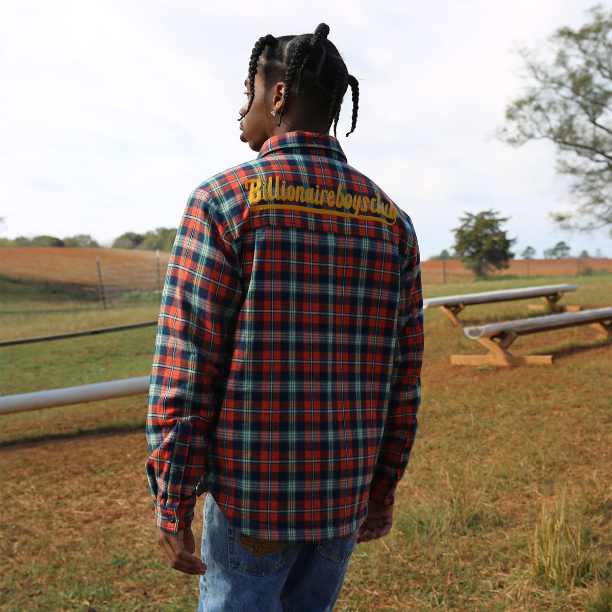 A man standing outside in a checked Billionaire Boys Club overshirt