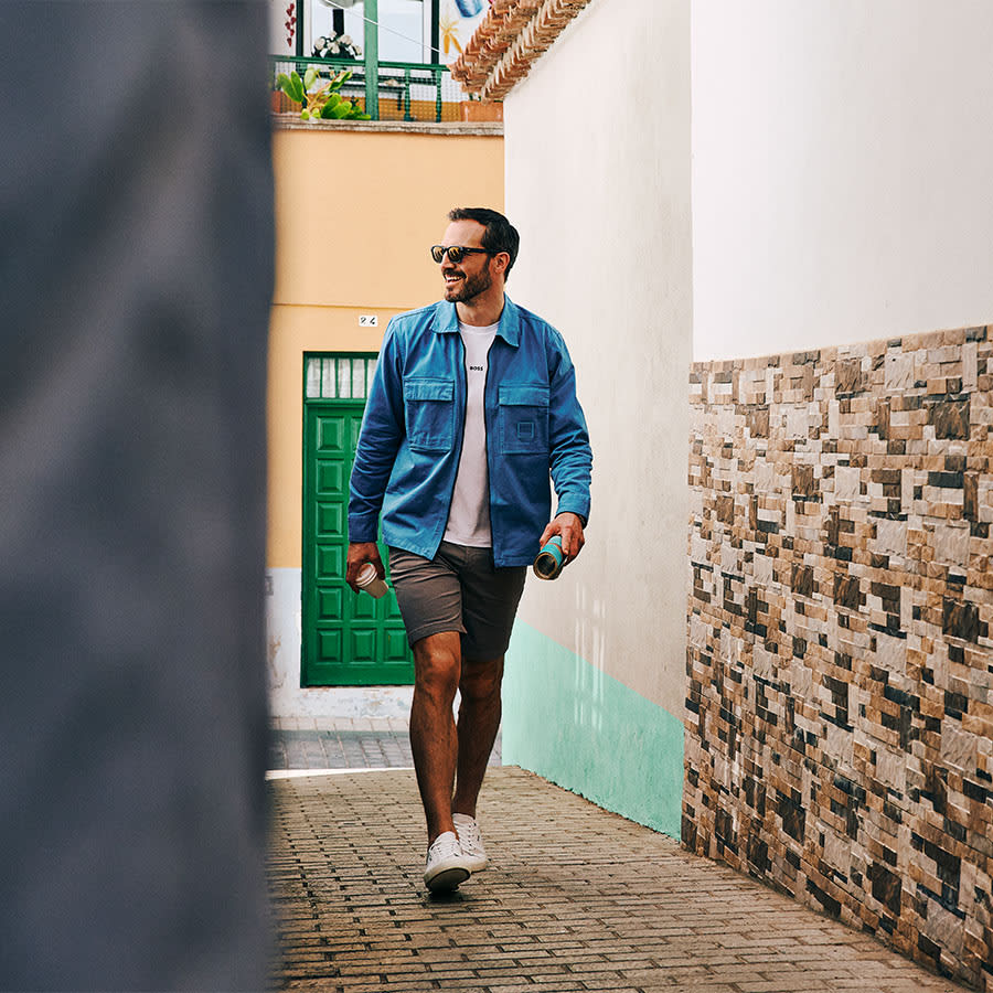 A man wearing BOSS looks happy strolling through village streets