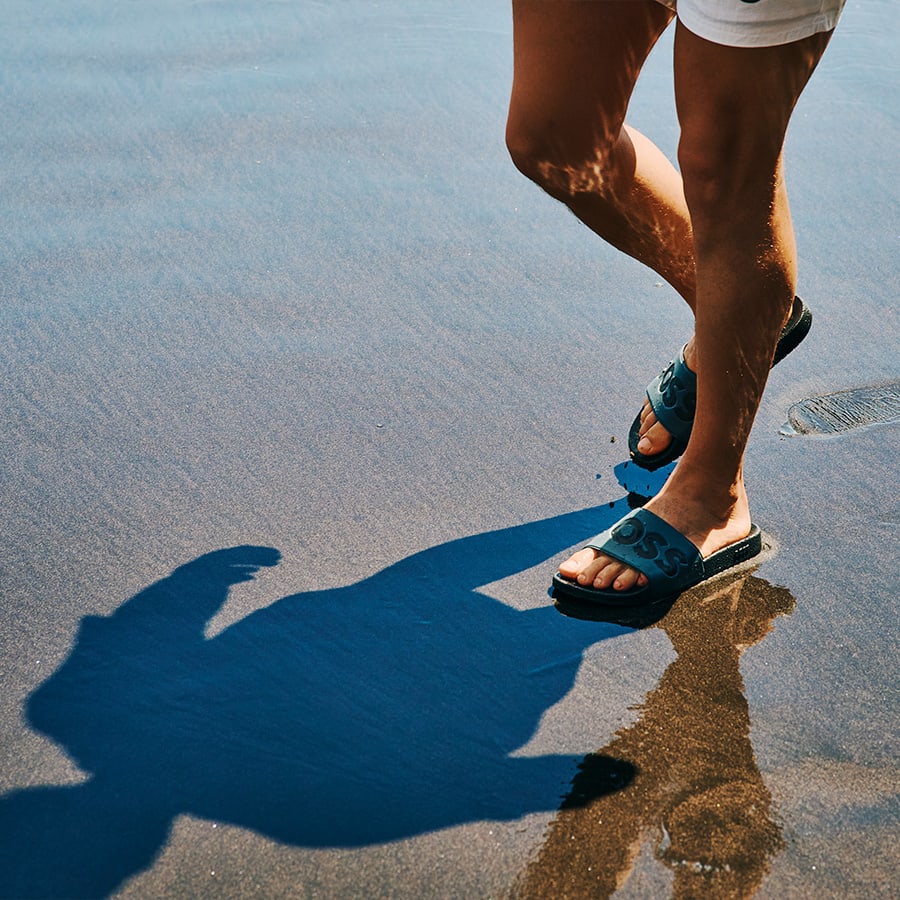 A man walking on the beach in sliders