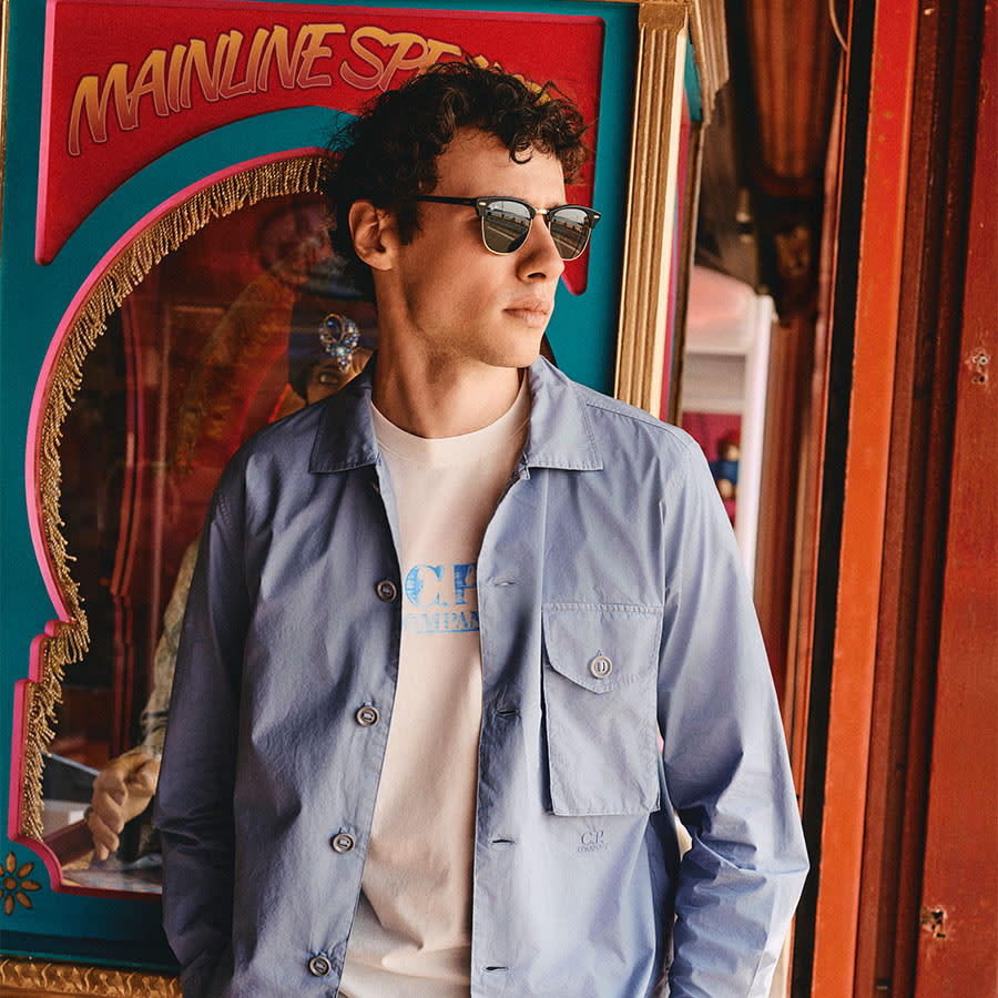 A man wearing a CP Company outfit looks thoughtful in front of an animatronic fortune teller