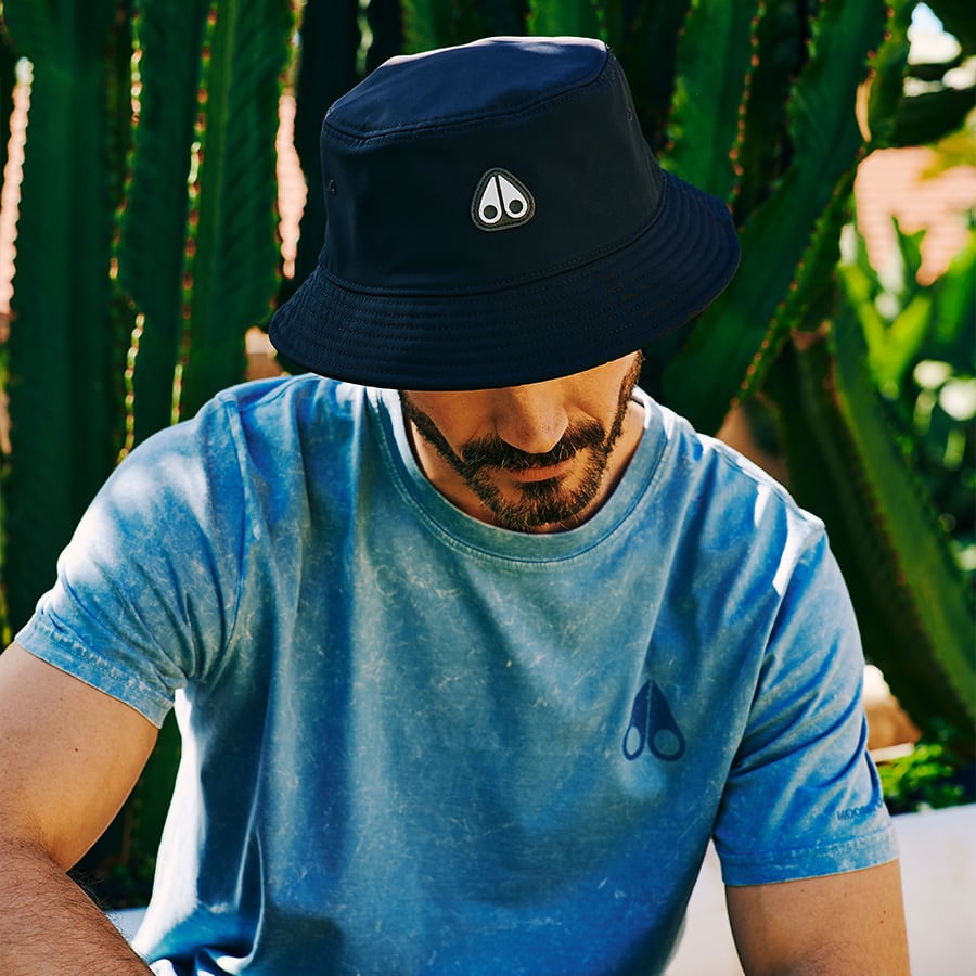 A man wears a blue T-shirt and bucket hat