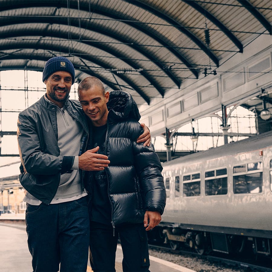 Two men embrace on a railway platform