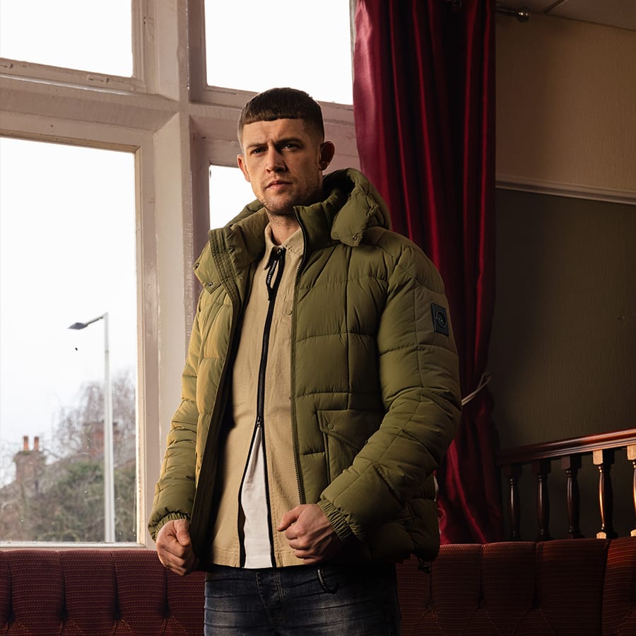 A man dressed in Marshall Artist standing by a pub window