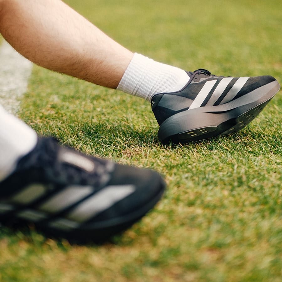 A pair of legs with running shoes on grass