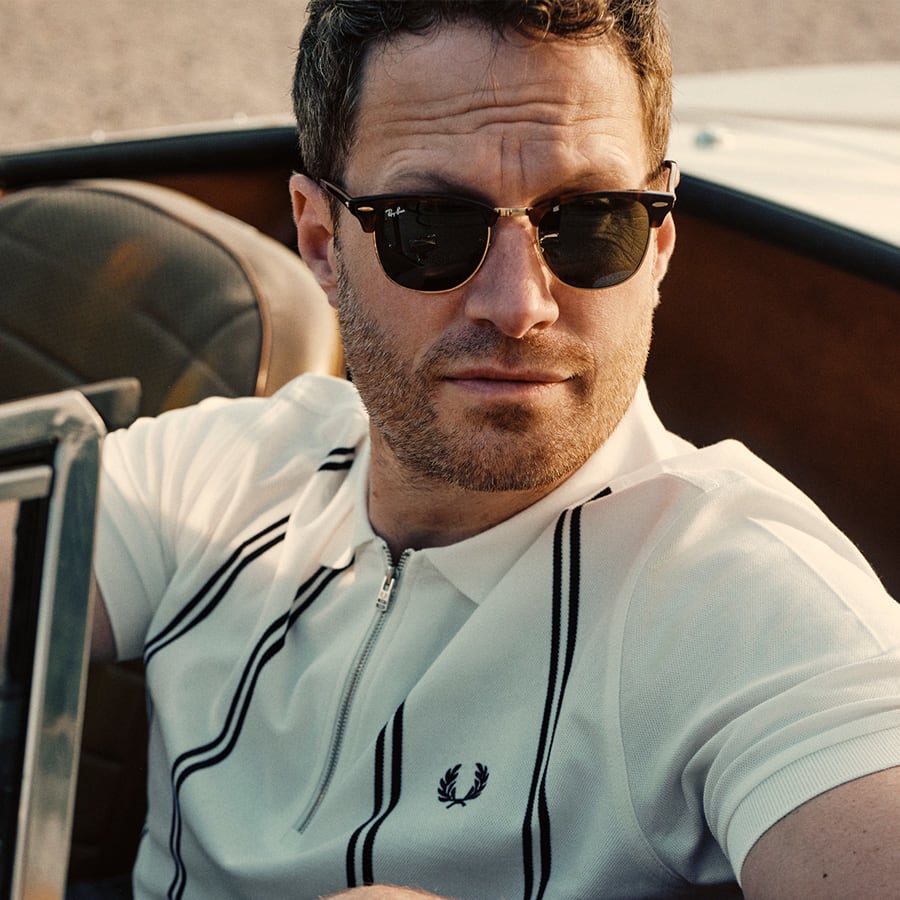 A man wearing Fred Perry clothes and Ray-Ban sunglasses