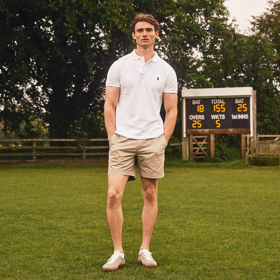 A man dressed in Ralph Lauren standing in front of a cricket scoreboard