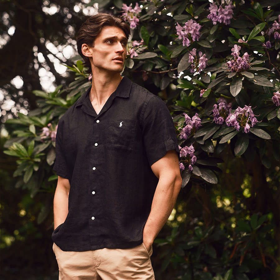 A man wearing Ralph Lauren standing in front of a bush