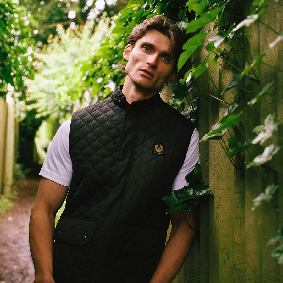 A man wearing Belstaff clothes from The Mainline Edit stands in a garden