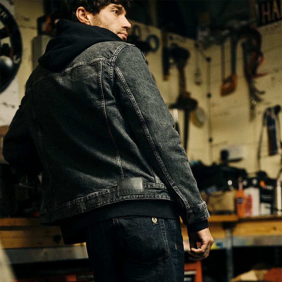 A man standing in a workshop wearing a Belstaff outfit 