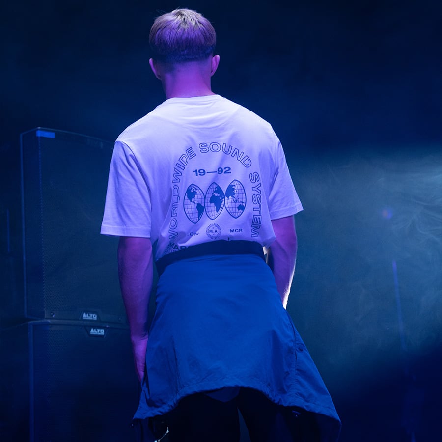 A man with his back to the camera in a Marshall Artist T-shirt